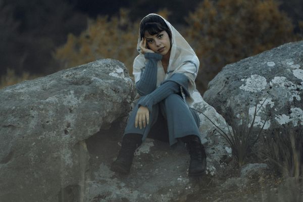 Person sitting in a calm meditative pose overlooking a beautiful landscape.